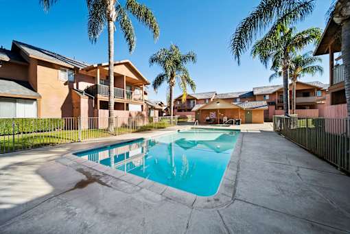 A swimming pool surrounded by palm trees and apartment buildings.