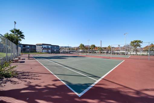 A tennis court with a red surface and white lines.
