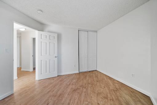 A room with white walls and wooden flooring with two white doors.