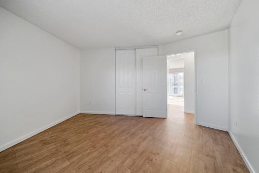 Empty room with white walls and wooden flooring.