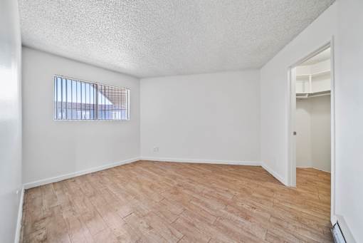 Empty room with a window and wooden flooring.