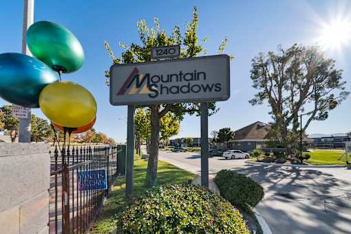 A sign for Mountain Shadows with balloons in front of it.