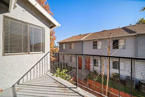 A balcony with a metal railing and a tree in the background.