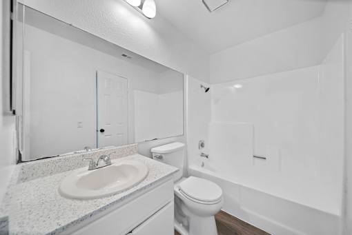 A white bathroom with a sink, toilet, and bathtub.