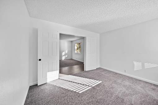 A room with a white door and a carpeted floor.