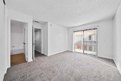 A room with white walls and a grey carpet.