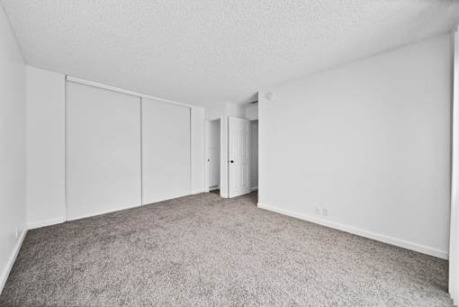 A room with white walls and grey carpet.