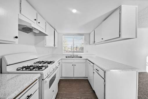 A white kitchen with a stove and cabinets.