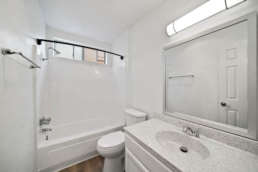 A white bathroom with a toilet, sink, and bathtub.