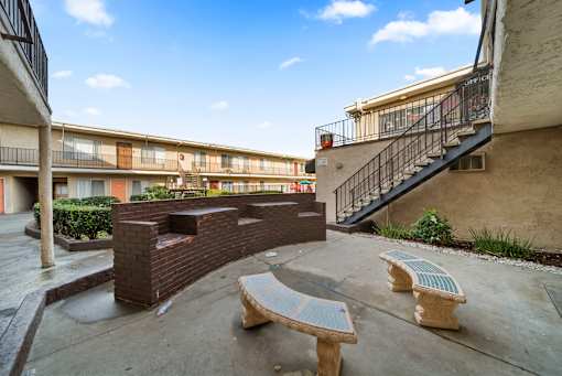 A courtyard with benches and a brick wall.