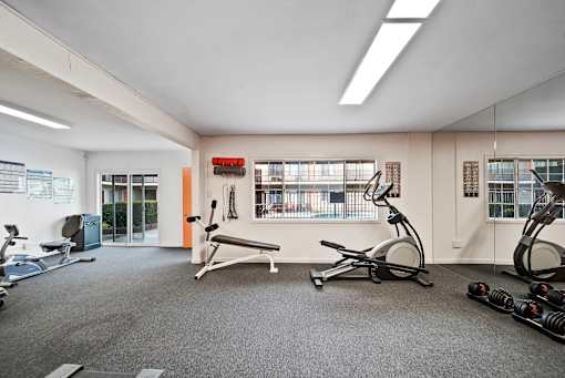 A gym with a variety of equipment including treadmills, weights, and exercise bikes.
