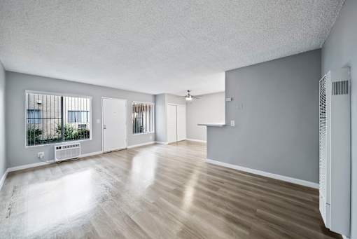 A spacious room with wooden flooring and white walls.