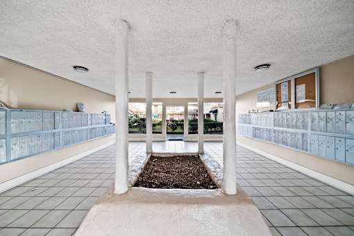 A long hallway with white columns and tiled floors.
