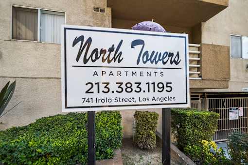 A sign for North Towers Apartments stands in front of a building.