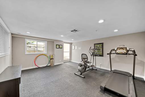 A spacious room with a treadmill, exercise bike, and a chair.