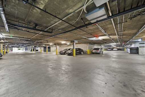 A parking garage with concrete floors and yellow poles.