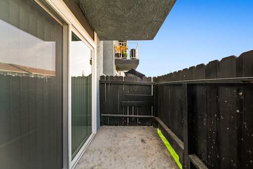 A balcony with a glass door and a yellow caution tape on the floor.