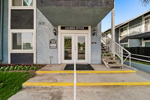 A building with a leasing office entrance has a yellow line painted on the concrete.