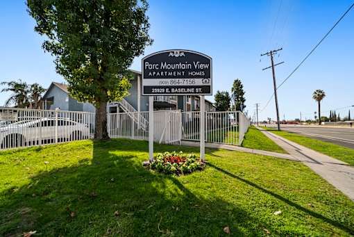 A sign for Parc Mountain View Apartment Homes stands in front of a fence.