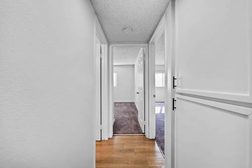 A hallway with white walls and a grey carpet.
