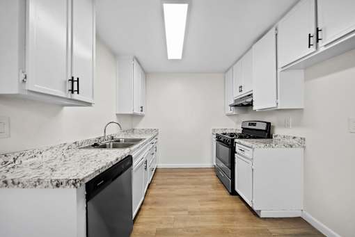 A kitchen with white cabinets and a marble countertop.