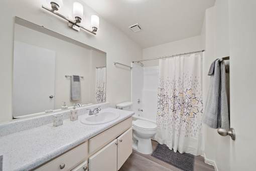 A white bathroom with a sink, toilet, and shower.