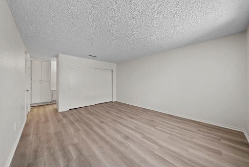 A room with a white ceiling and light wood flooring.