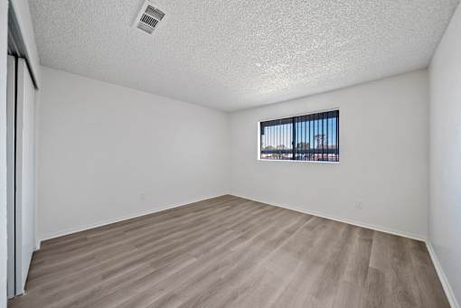 A room with a window and a wooden floor.