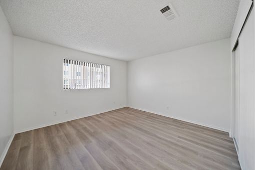 Empty room with a window and wooden floor.