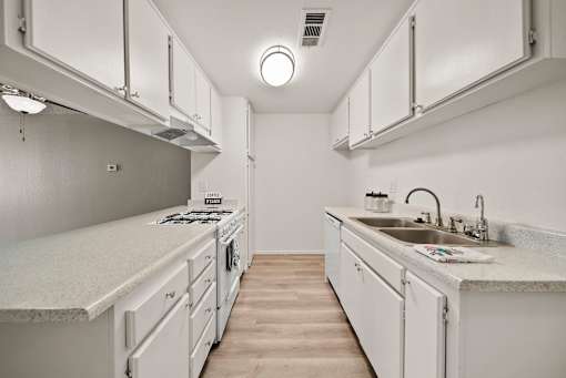 A white kitchen with a sink and a stove.