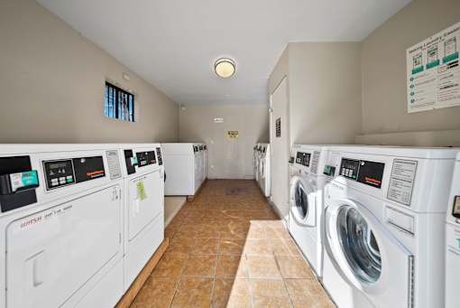 A laundry room with a row of washers and dryers.