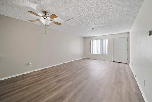 A room with a ceiling fan and wooden flooring.