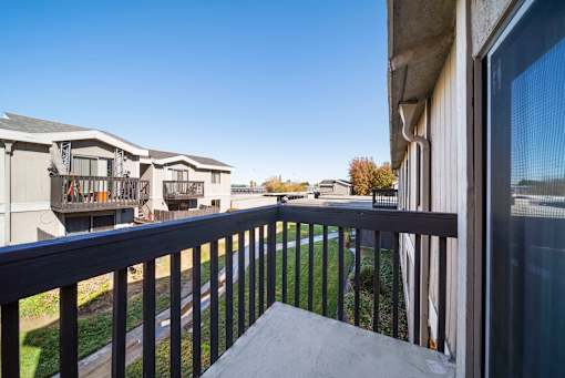 A balcony with a black railing and a view of apartment buildings.