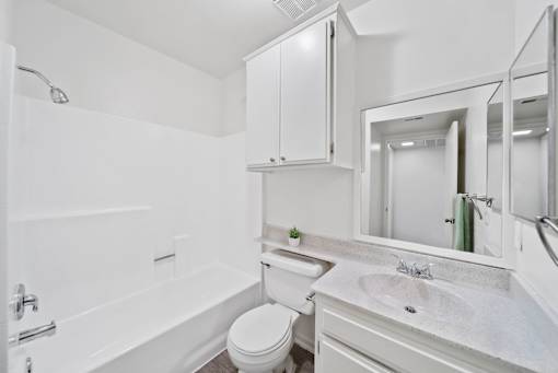 A white bathroom with a toilet, sink, and bathtub.