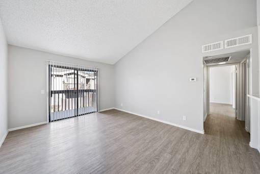 A room with a sliding glass door and a wooden floor.