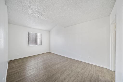 A room with a window and wooden flooring.