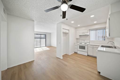 A white kitchen with a fan on the ceiling.