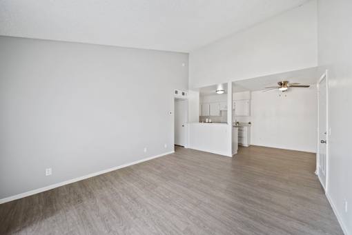 A spacious room with a kitchenette and a ceiling fan.