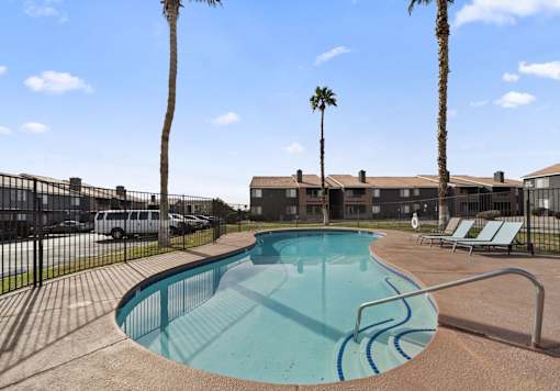 A swimming pool surrounded by palm trees and lounge chairs.
