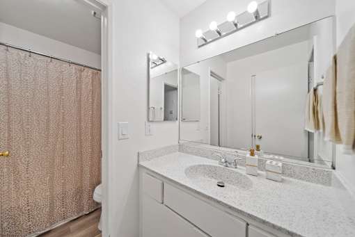 A bathroom with a sink, mirror, and shower curtain.