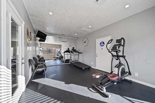 A modern home gym with a treadmill, elliptical trainer, and other exercise equipment.