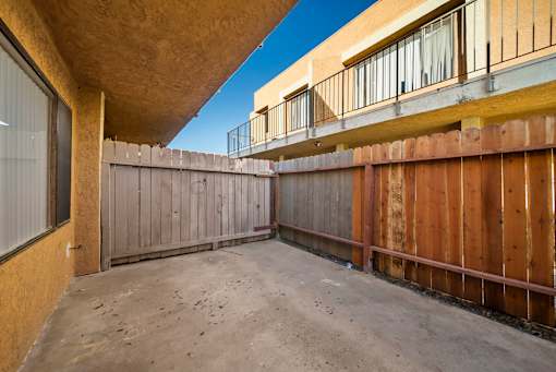 A backyard with a wooden fence and a concrete floor.