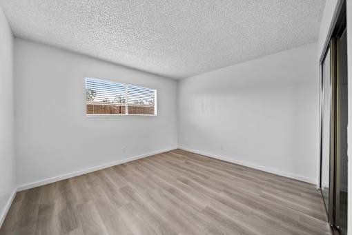 Empty room with wooden flooring and a window.