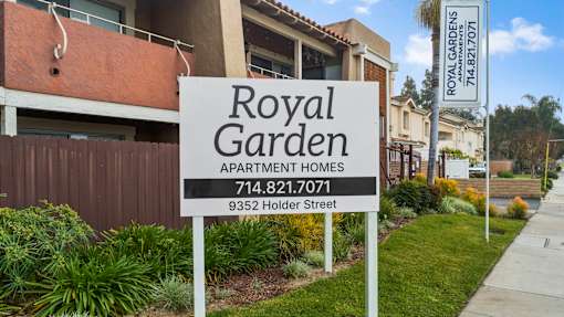 A sign for Royal Garden Apartment Homes stands in front of a building.