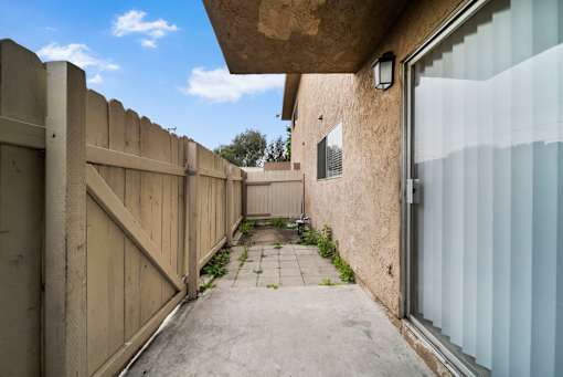 A narrow alley with a wooden fence on the left and a concrete wall on the right.