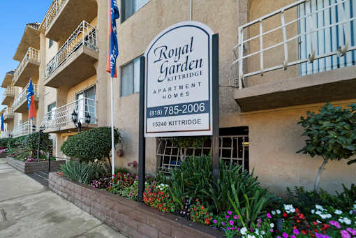 A sign for Royal Garden Apartment Homes is displayed in front of a building.
