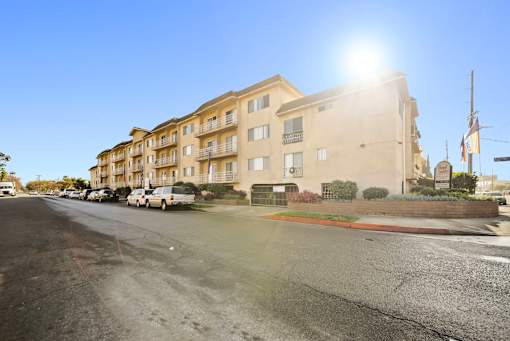 A sunny day in front of a beige apartment building.