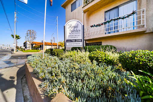 A sign for Royal Garden Apartments stands in front of a building.
