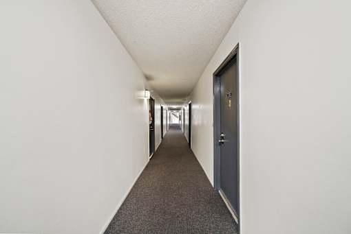 A long hallway with a carpeted floor and white walls.