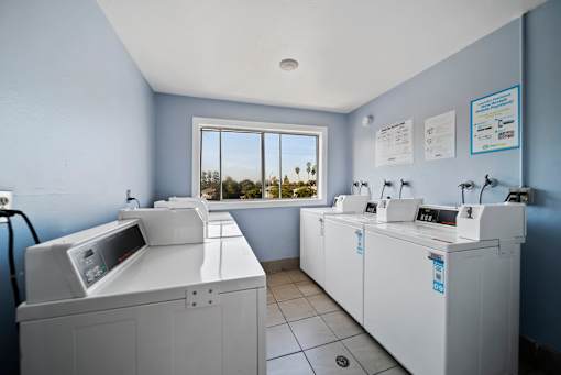 A room with two washing machines and a window overlooking a desert landscape.